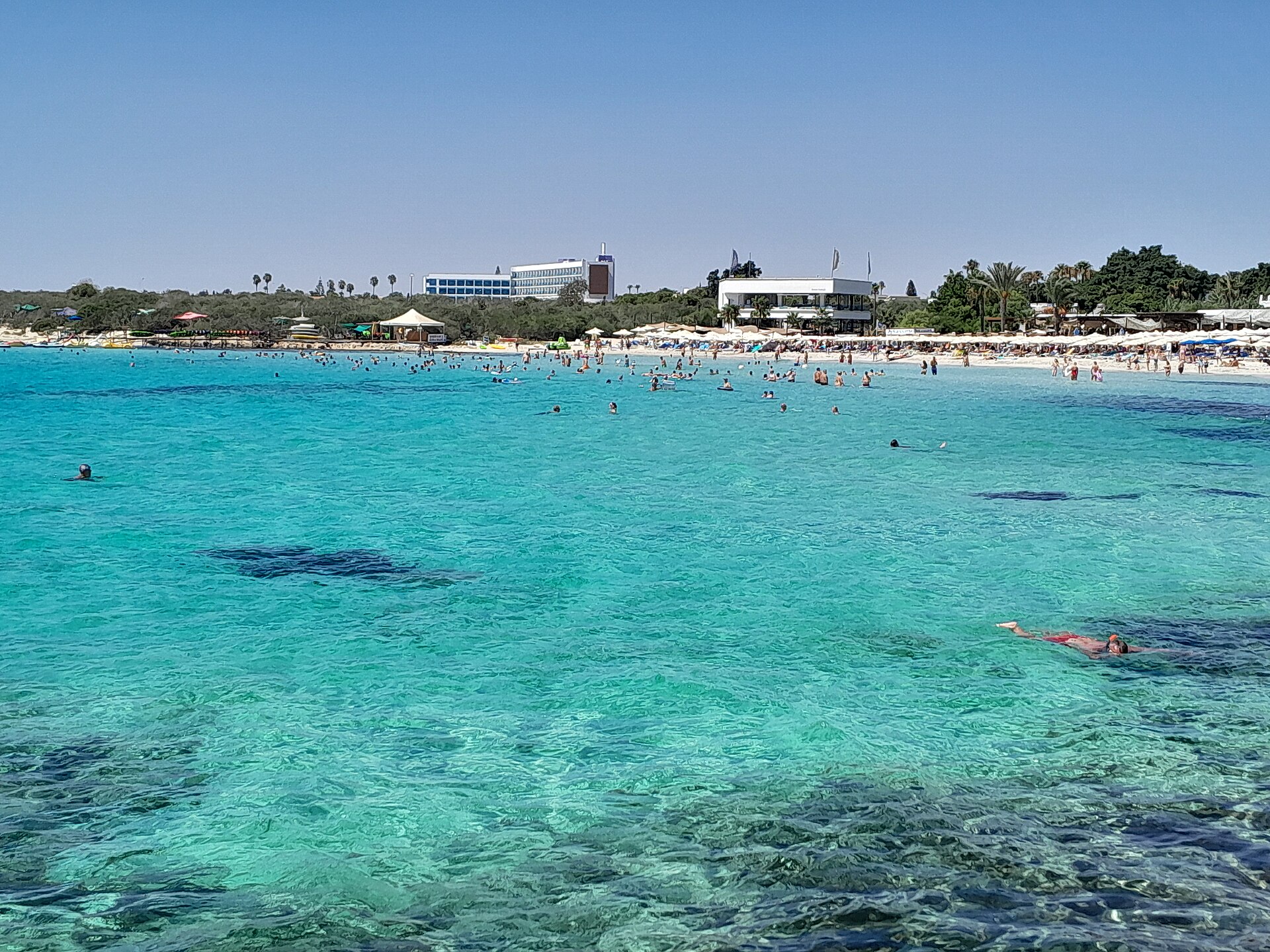 Turkost vatten vid Nissi Beach med hotellen längs stranden